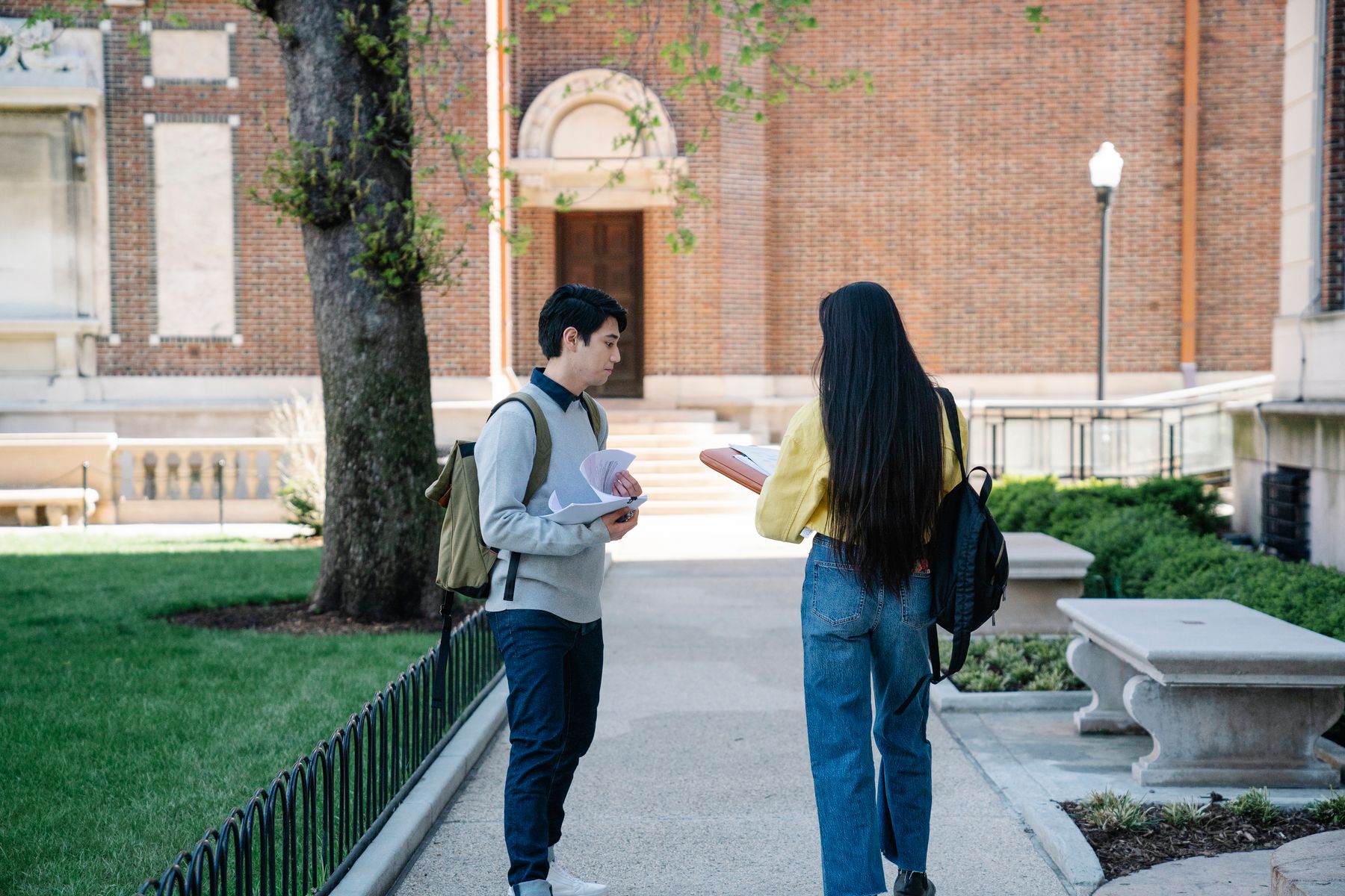 Two college students with backpacks talking on a university campus